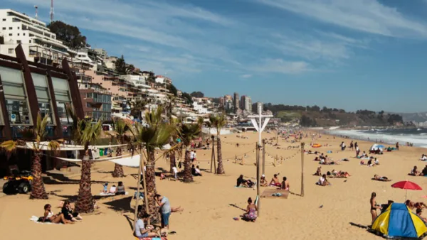 Praia de Reñaca com banhistas, palmeiras na areia e edifícios residenciais na encosta ao fundo, Chile