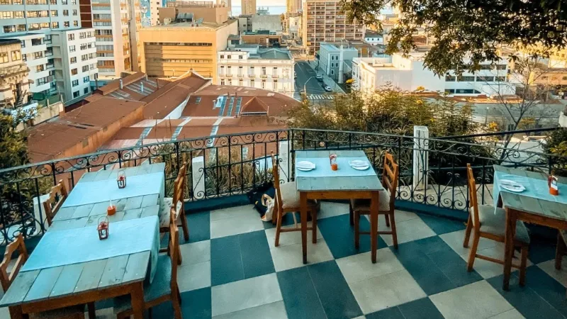 Rooftop terrace of La Caperucita y el Lobo restaurant with wooden tables and panoramic views of Valparaíso cityscape