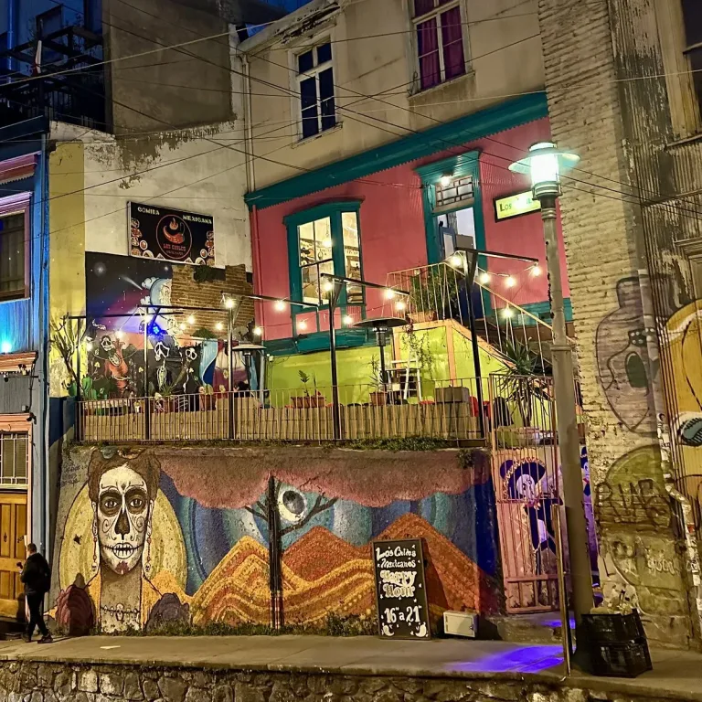 Calle de Valparaíso de noche con edificios coloridos, murales urbanos y restaurante de comida mexicana iluminado con luces